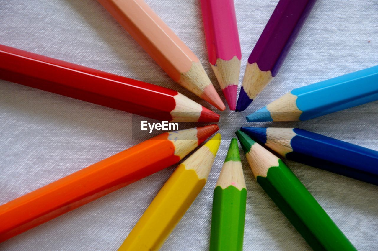 Close-up of colorful pencils arranged on white paper