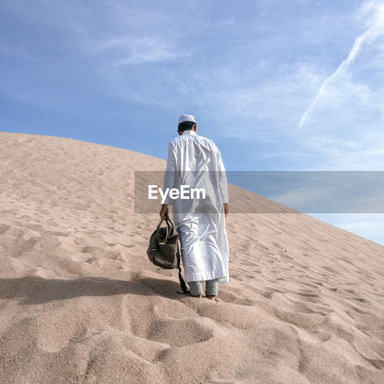 Rear view of man standing on desert against sky