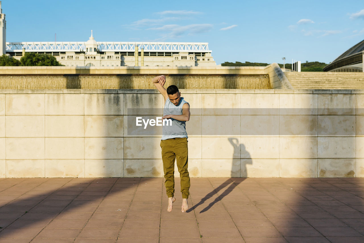 Male dancer jumping on footpath during sunny day