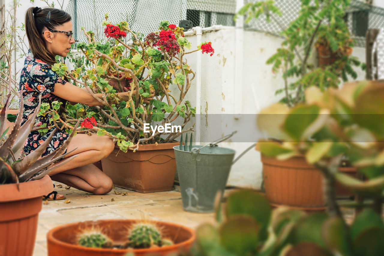 WOMAN SITTING IN POTTED PLANT