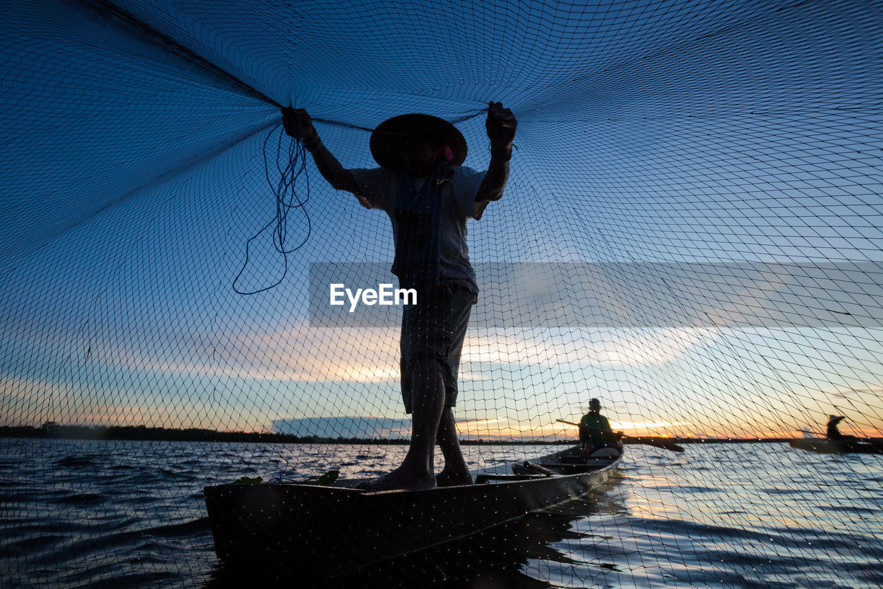 Man with fishing net during sunset