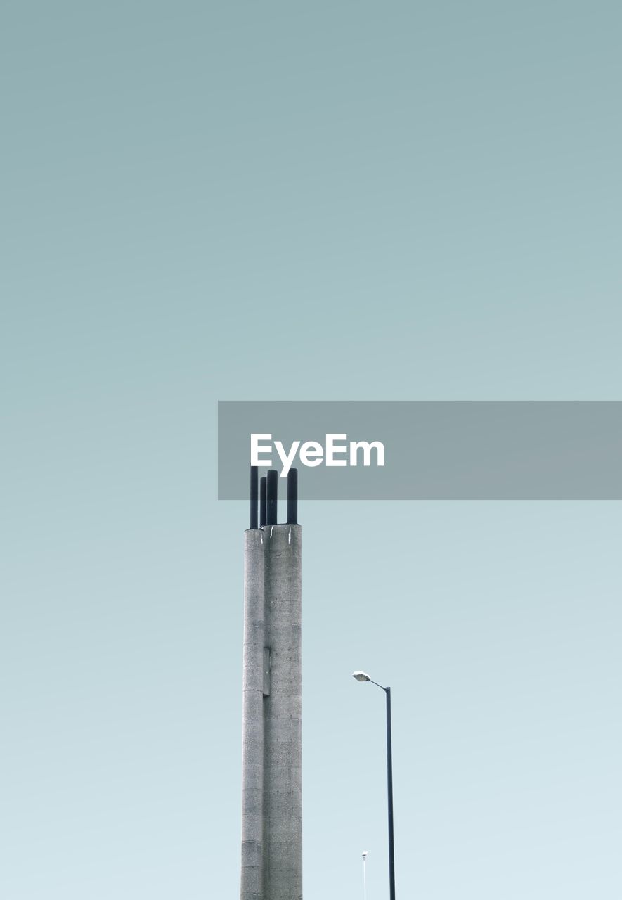 Low angle view of column and street light against blue sky