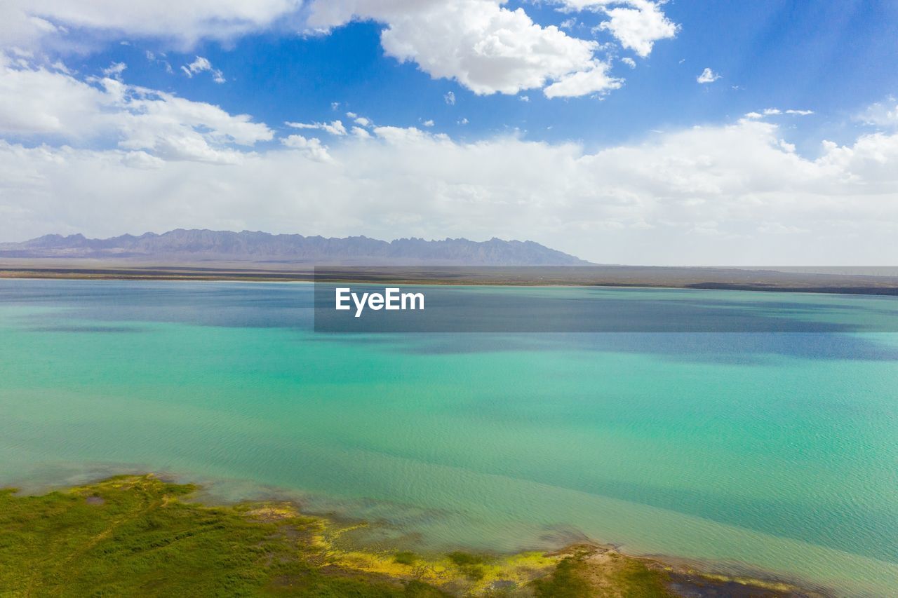 SCENIC VIEW OF SEA AND MOUNTAINS AGAINST BLUE SKY