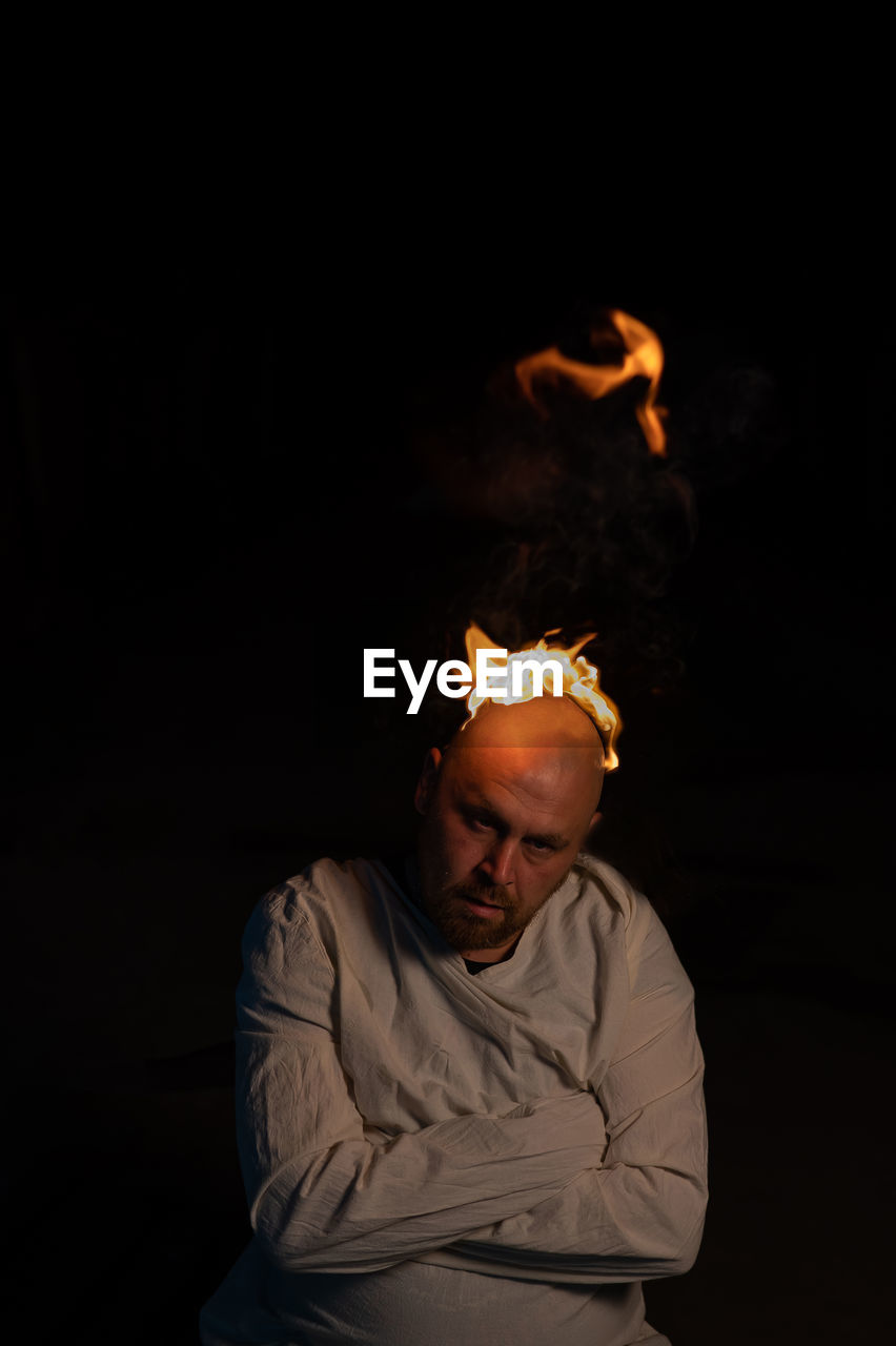 Man holding burning candle against black background