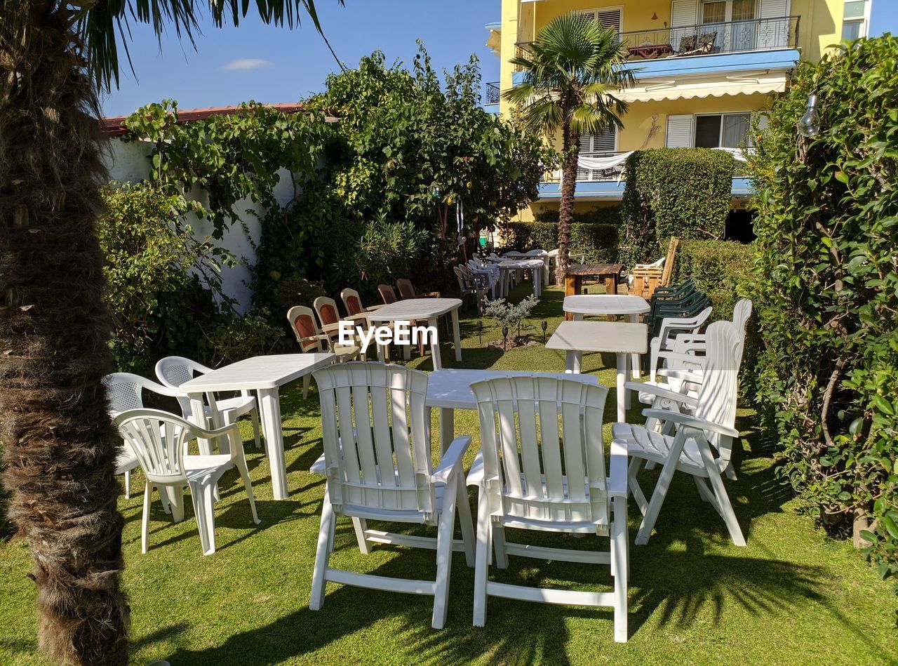 EMPTY CHAIRS AND TABLES IN LAWN