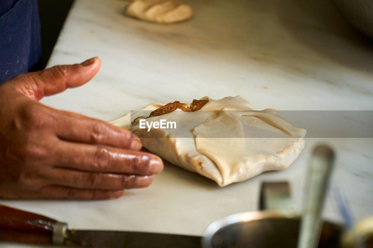 Midsection of person preparing murtabak in kitchen