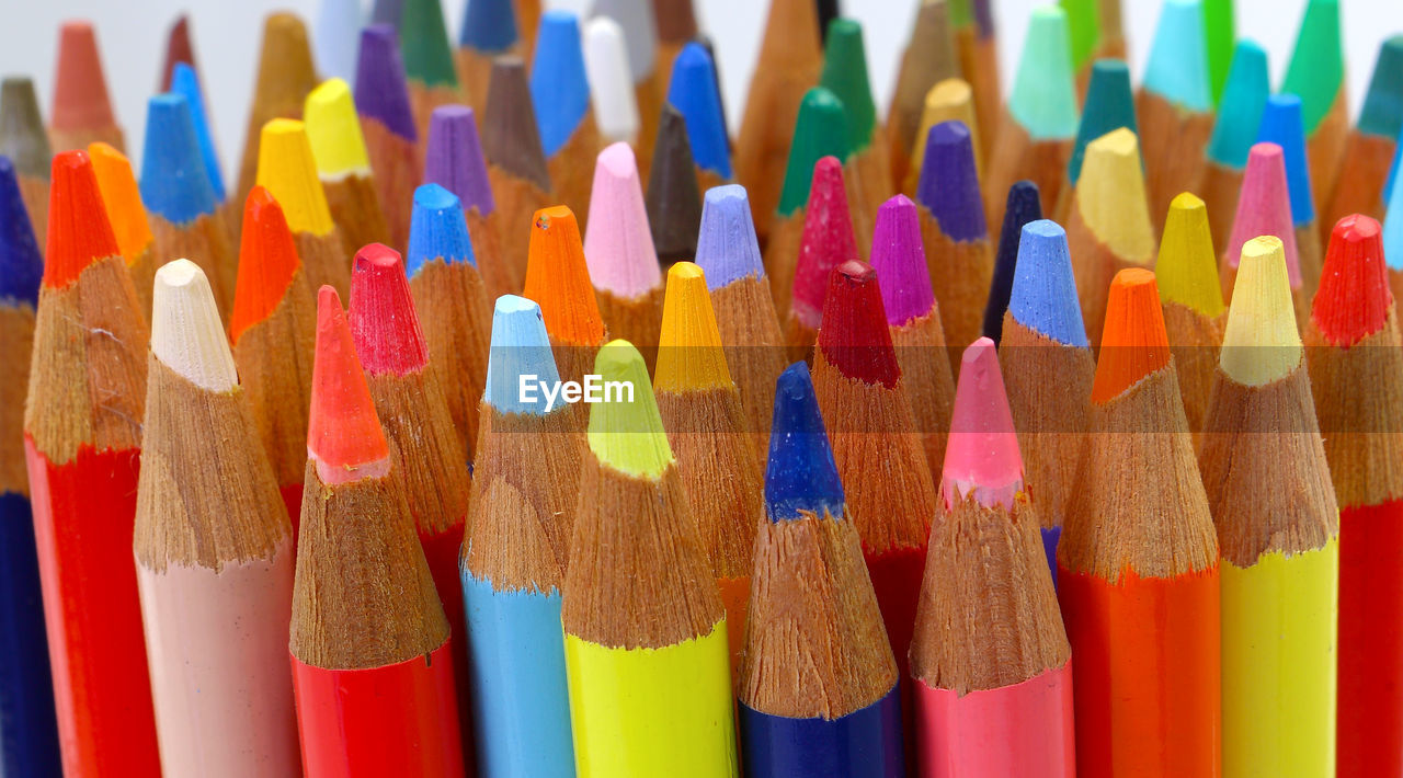 CLOSE-UP OF MULTI COLORED PENCILS ON COLORFUL SHELF