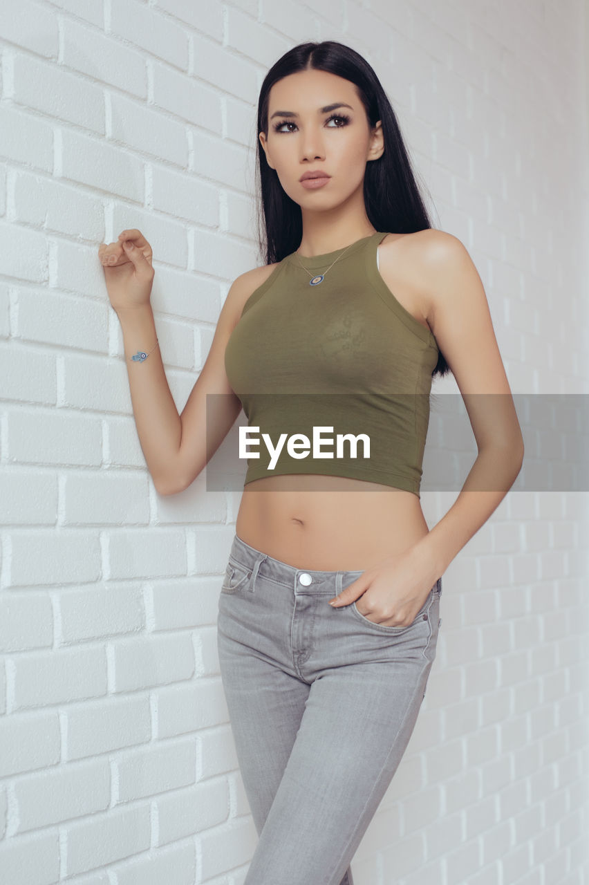 Portrait of woman standing against wall