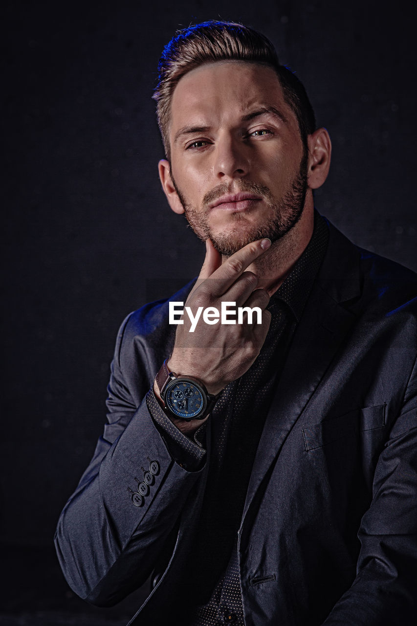 Portrait of young man against black background