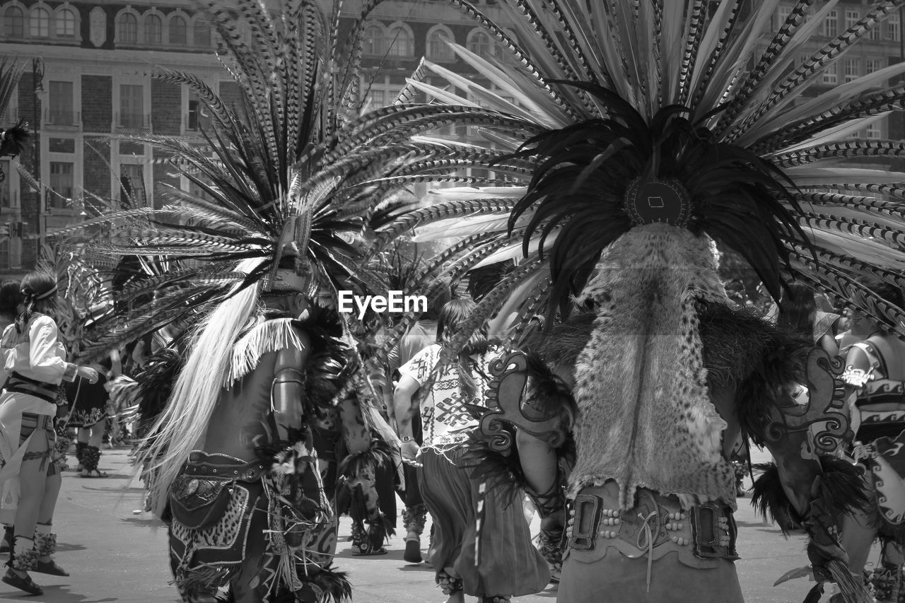 group of people, black and white, monochrome, architecture, monochrome photography, clothing, crowd, carnival, palm tree, person, men, tradition, built structure, adult, large group of people, dancing, city, tropical climate, arts culture and entertainment, celebration, traditional clothing, day, women, building exterior, outdoors