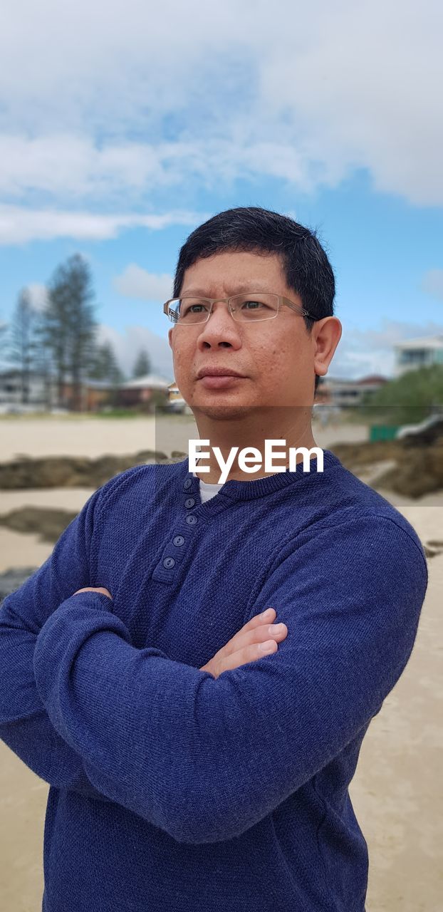 Handsome man with arms crossed standing at beach