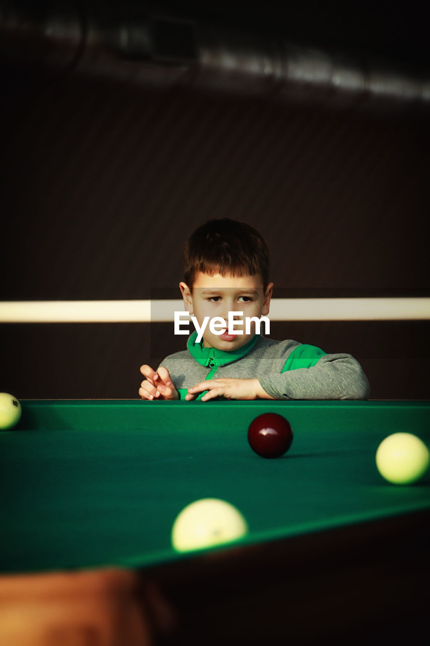 Boy looking at balls on pool table