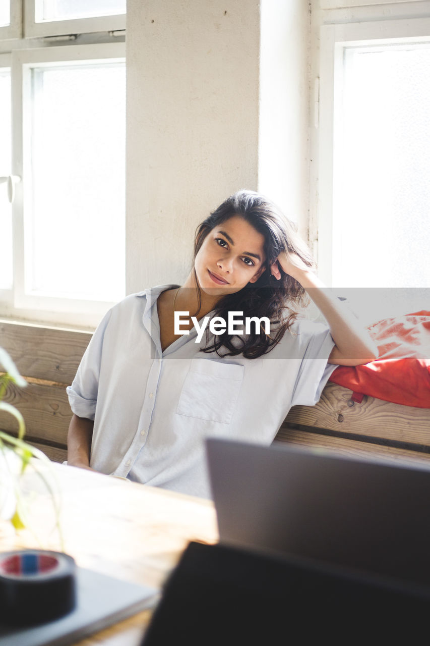 Portrait of young female computer programmer sitting in creative office