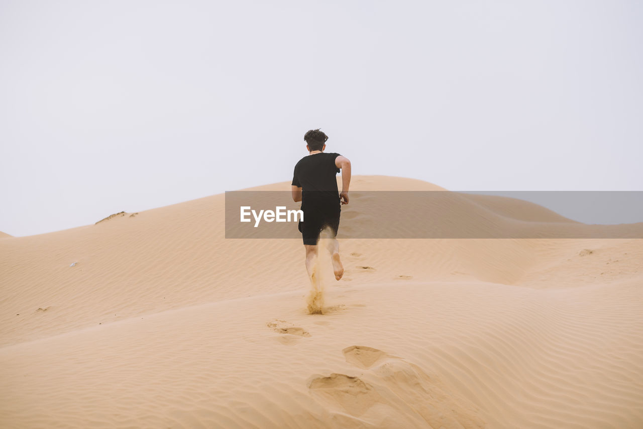 Rear view of man on sand dune in desert