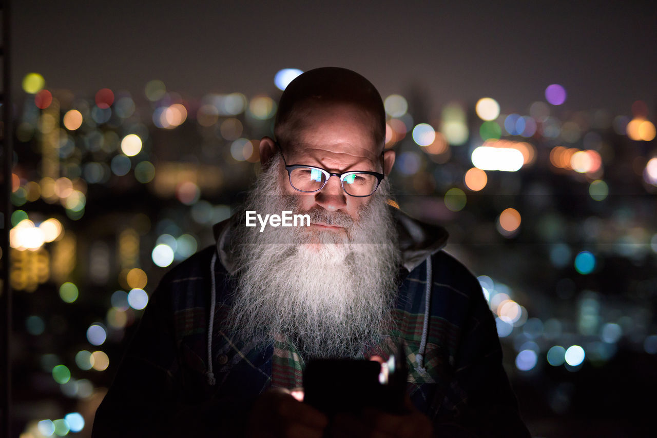 Portrait of man with illuminated lighting equipment at night