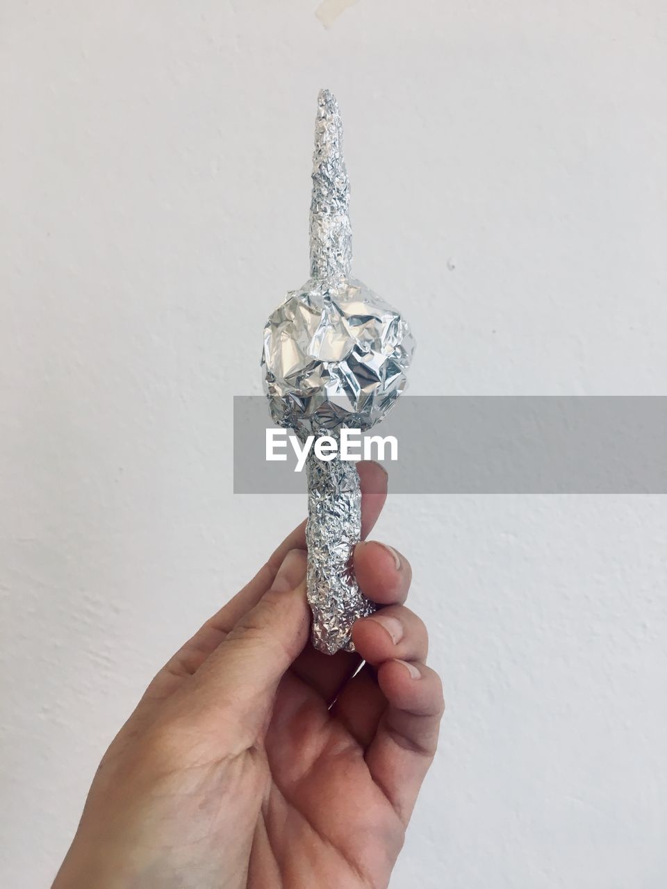 Cropped hand holding foil against wall