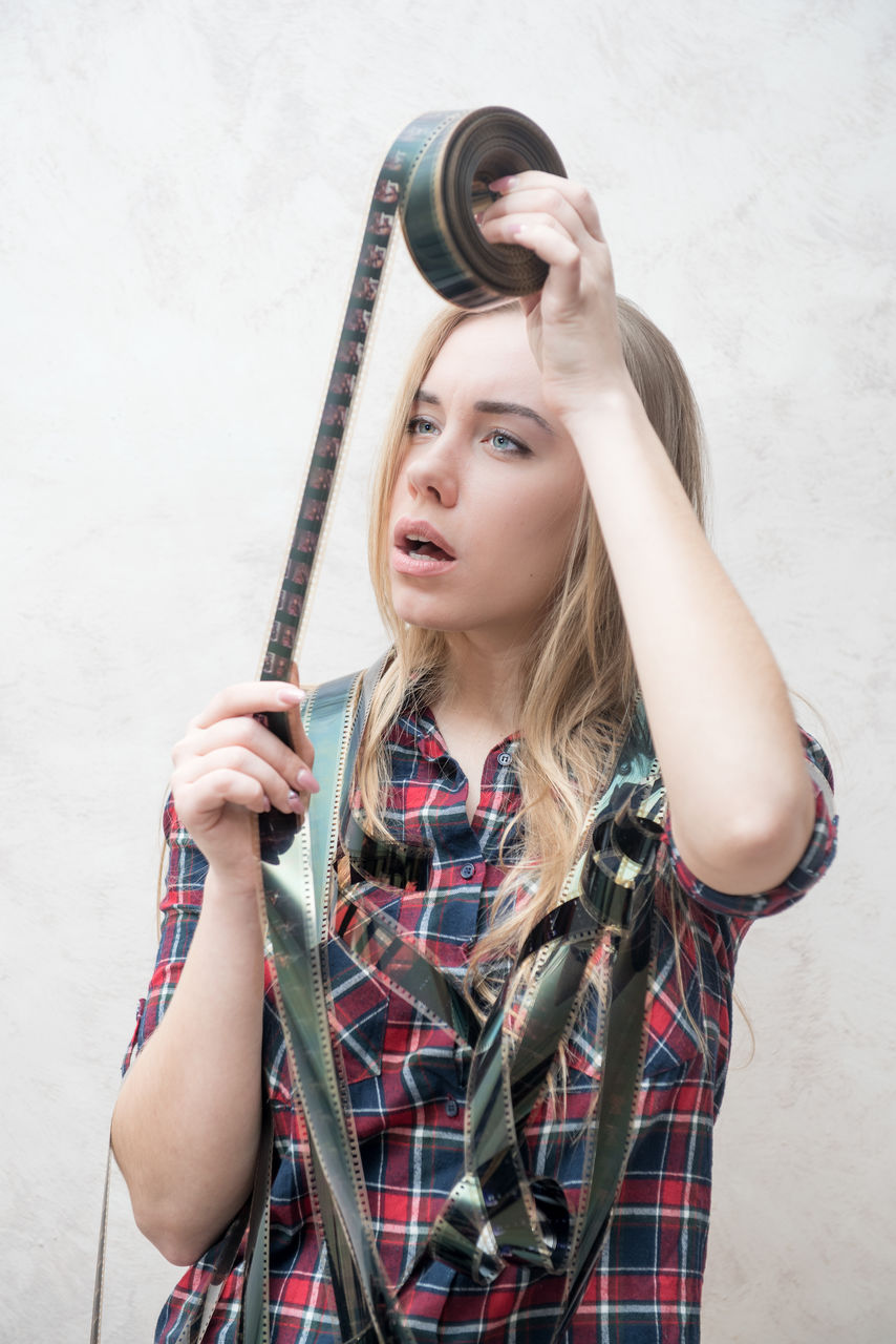 Close-up of woman looking at film reel against wall