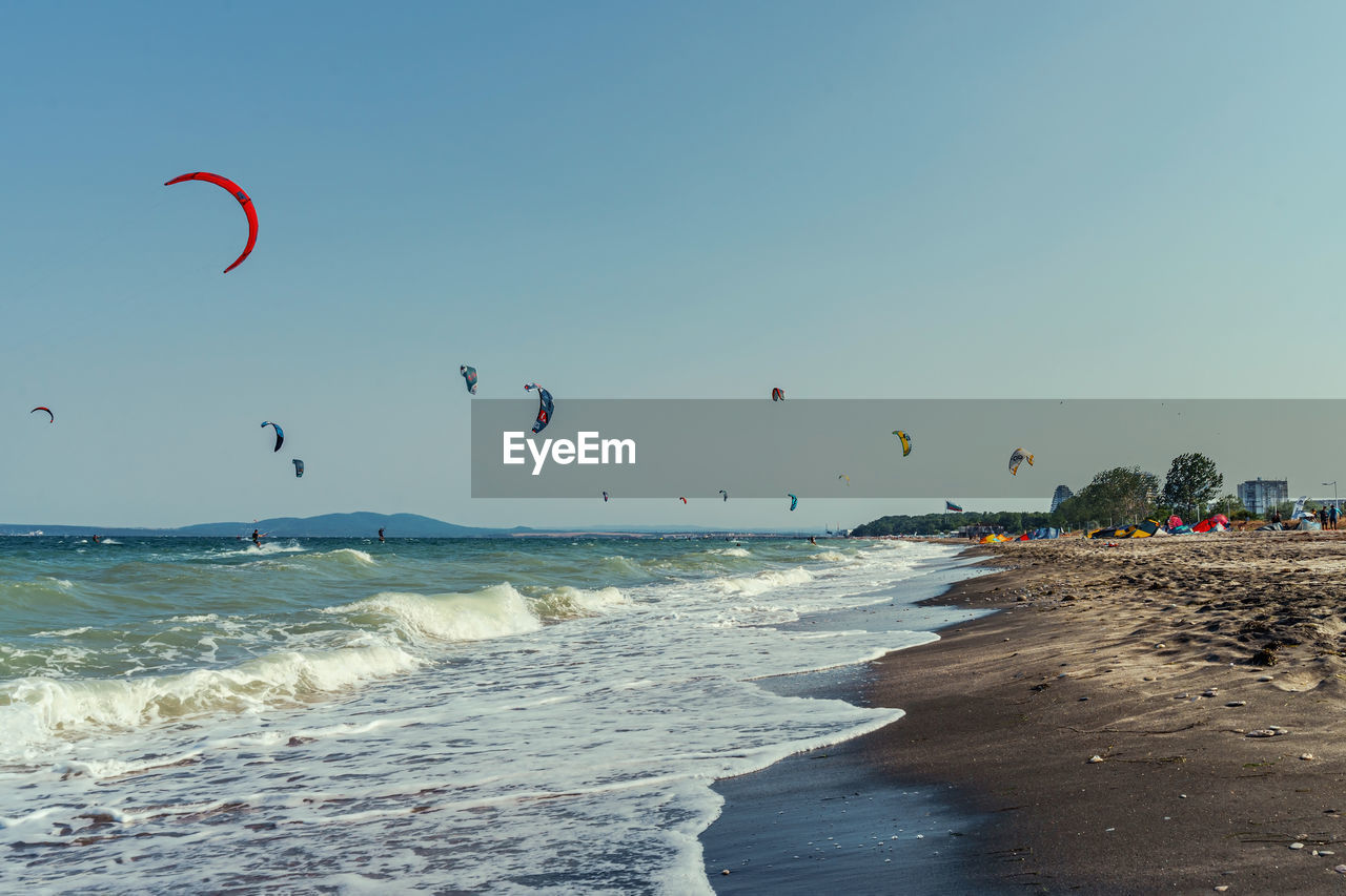 Kite surfers on the beach against sky.