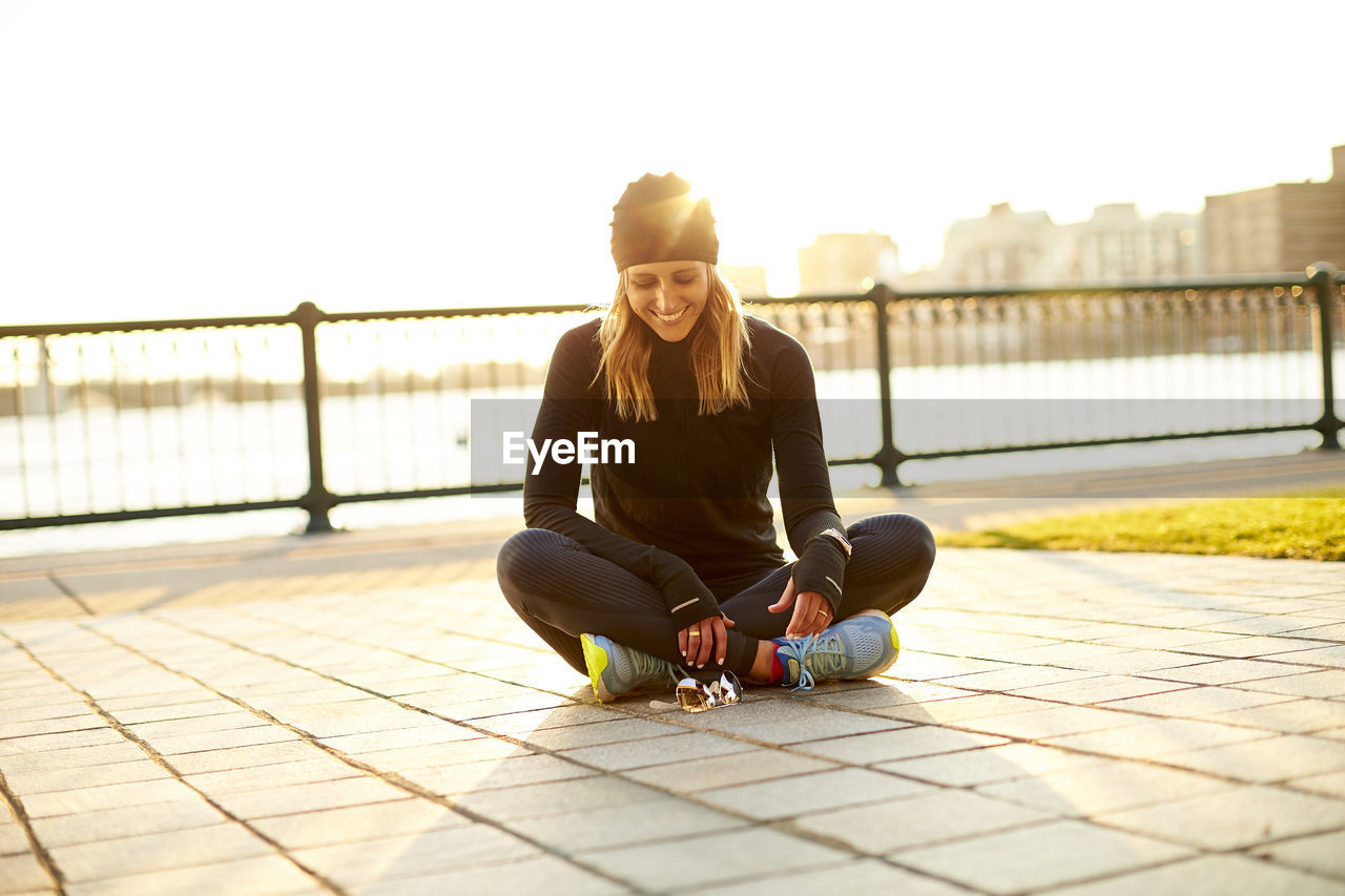 A happy backlit portrait of a female runner at rest.