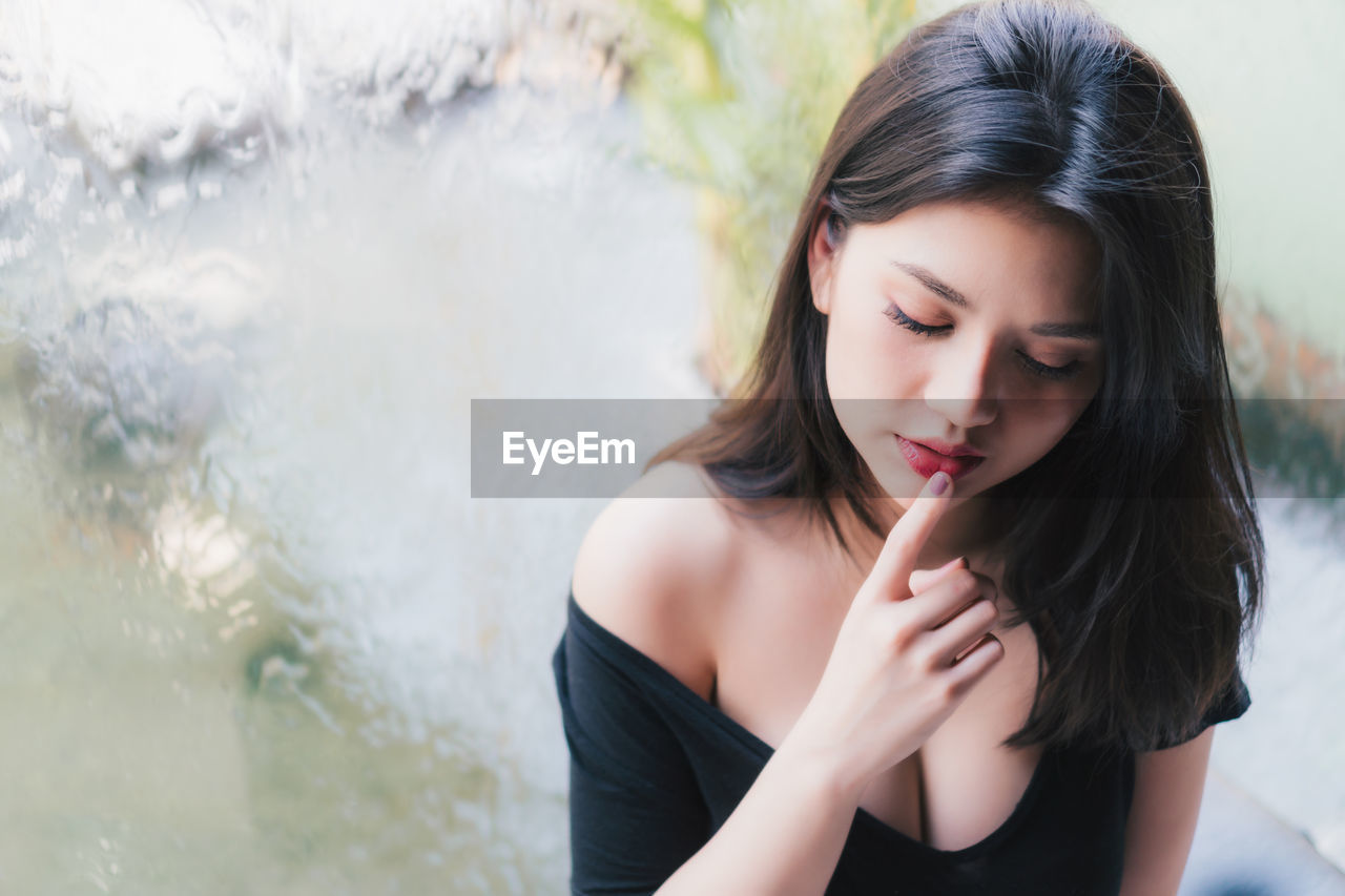 High angle view of young woman with finger on lips sitting by window