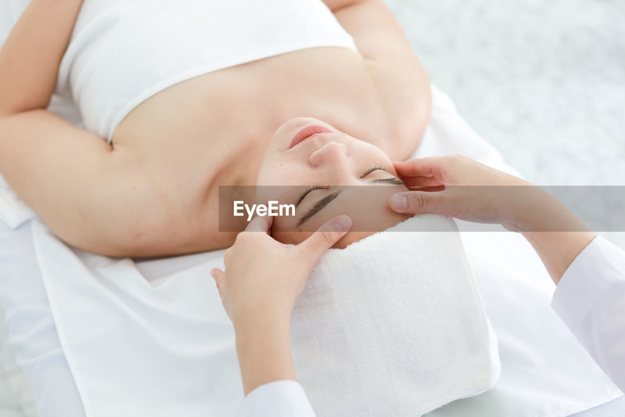 Cropped hands of woman massaging customer lying on table