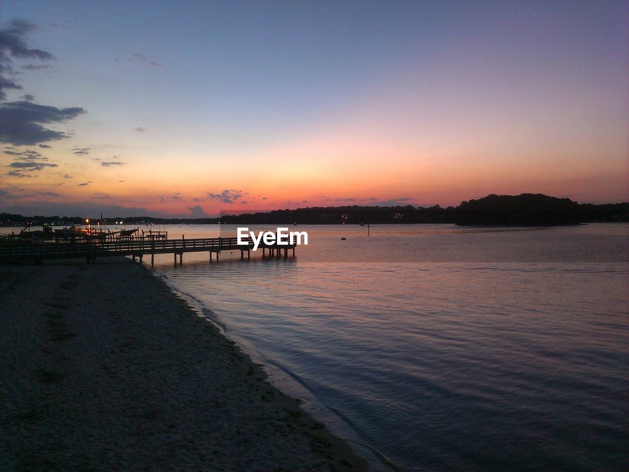 Jetty at distance in calm sea at dusk