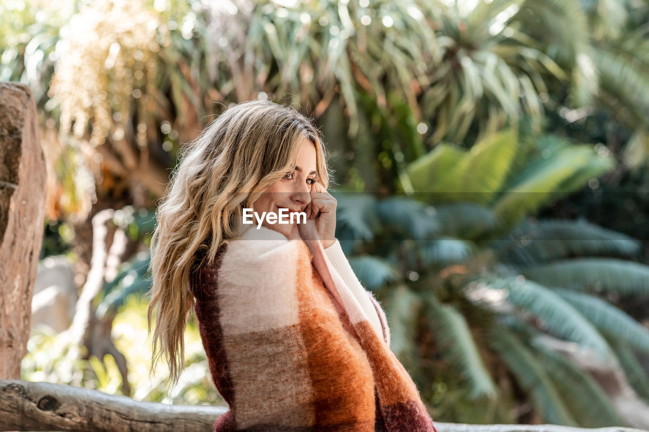 Fashionably dressed blonde-haired young woman in a park on an autumn day