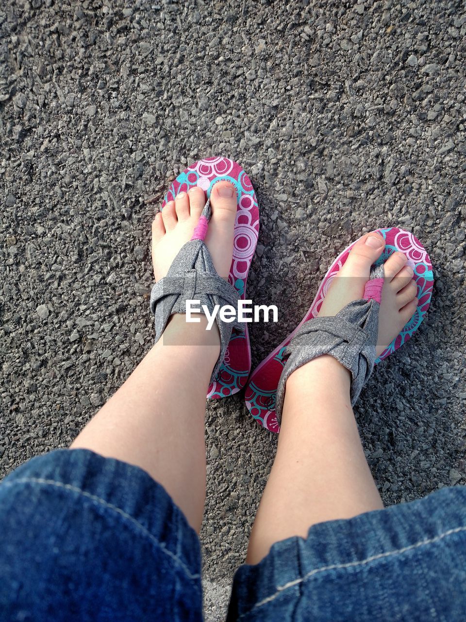 Low section of girl wearing flip-flop on road