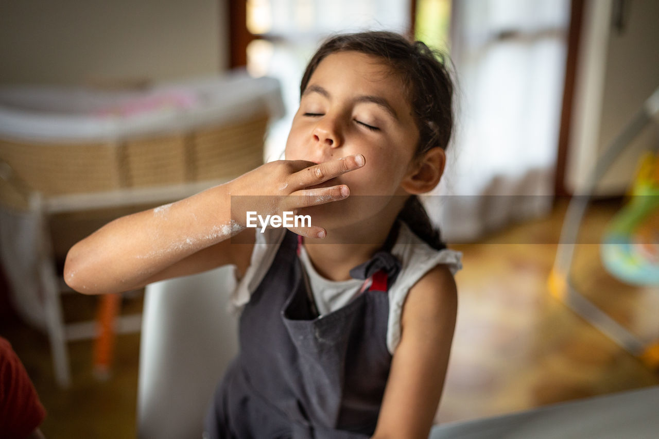 Girl wearing grey apron tasting sugar