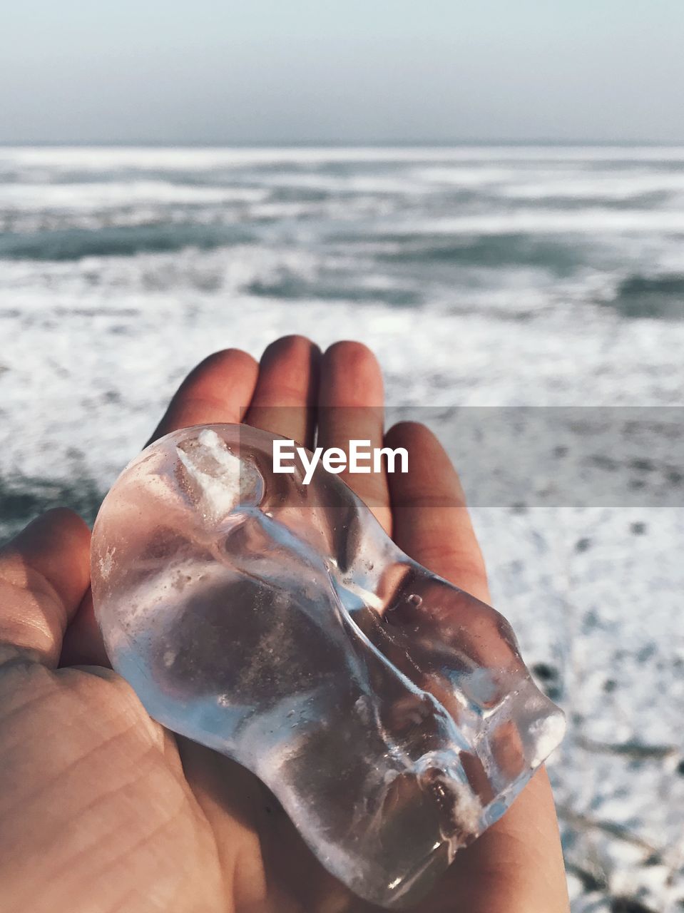 Cropped hand holding ice at beach