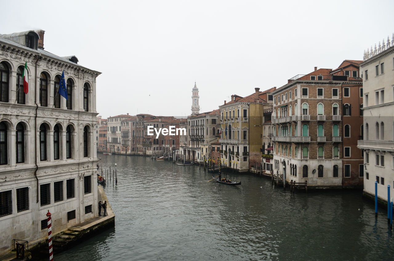 Canal amidst buildings against sky