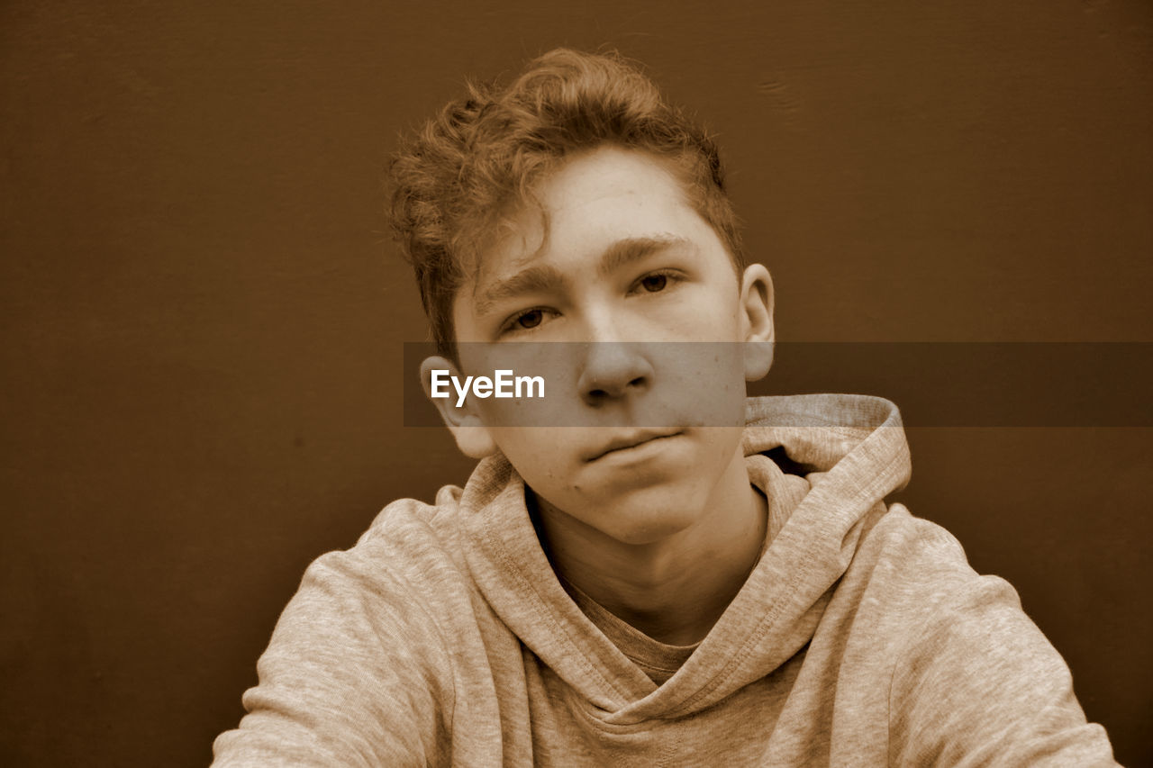 Portrait of teenage boy against brown background