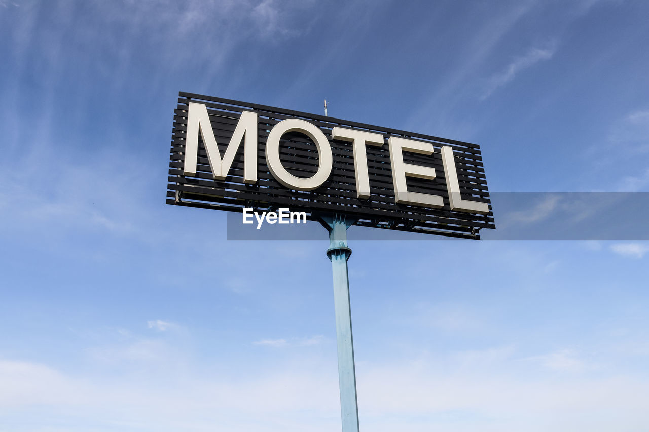 Low angle view of motel sign against blue sky