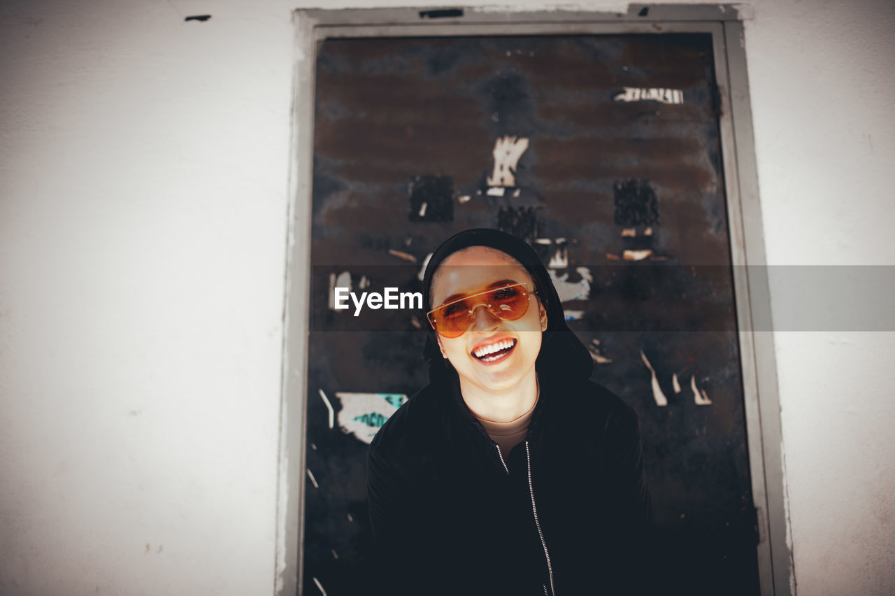 Smiling woman standing against wall