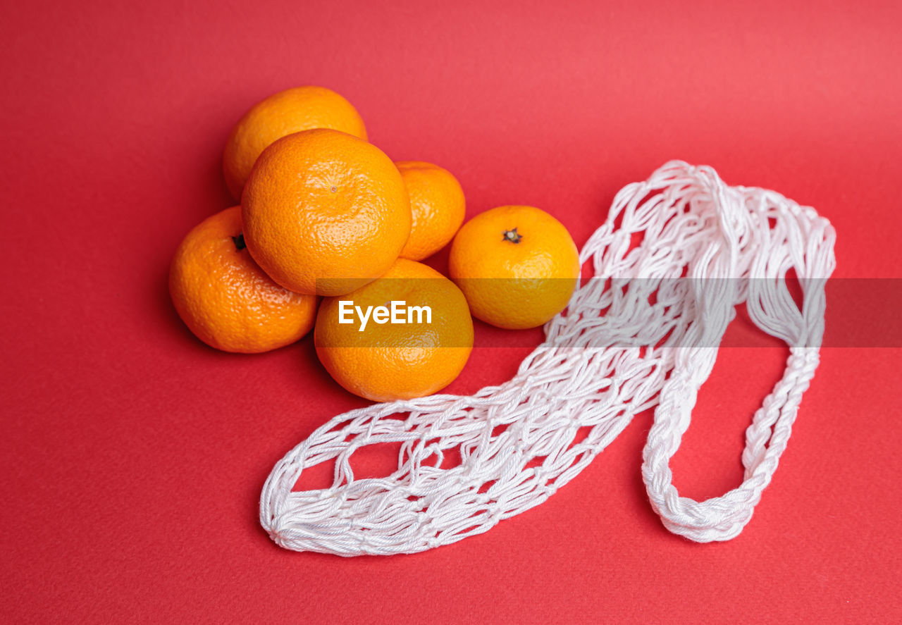 Eco-friendly mesh with tangerines on a red festive background. feast of the nativity of christ.