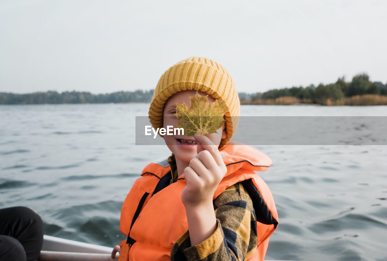 Young boy on a fishing boat holding a maple leaf up looking happy