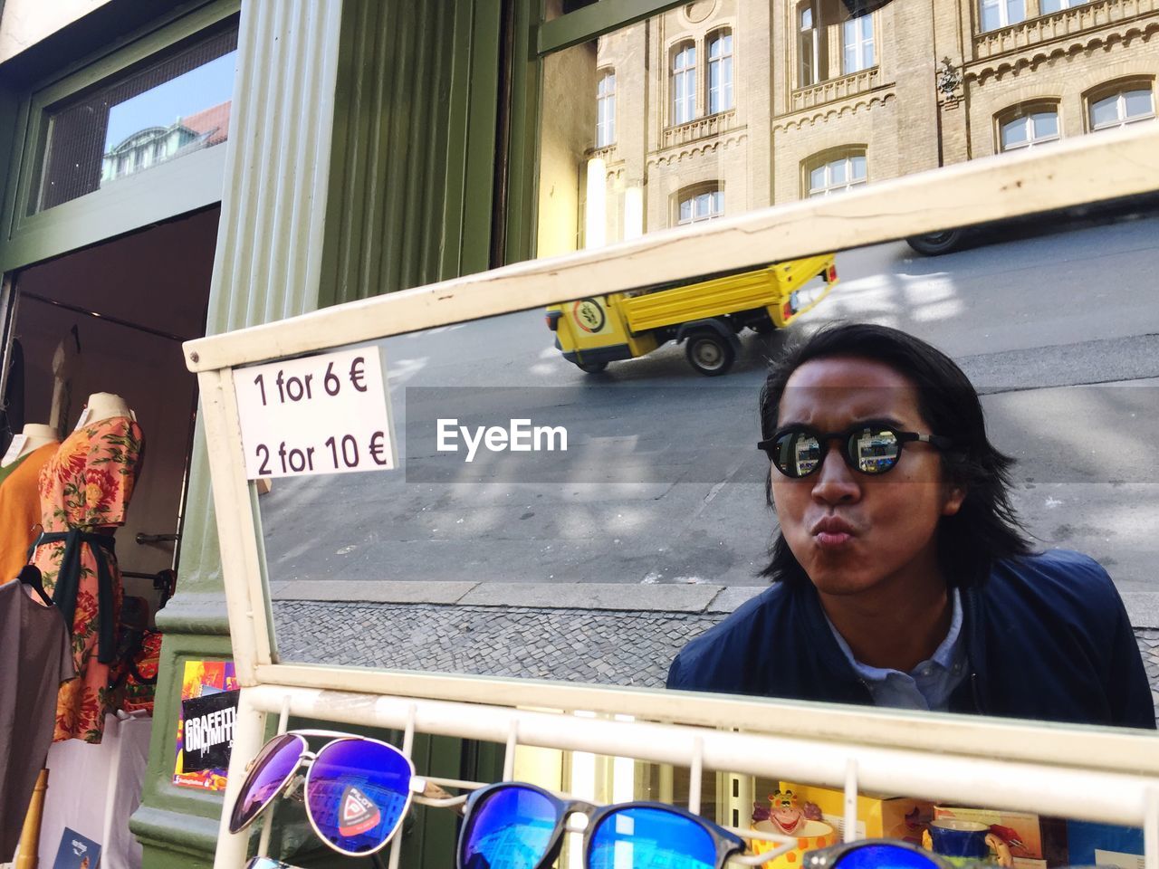 Reflection of man wearing sunglasses while puckering lips on mirror