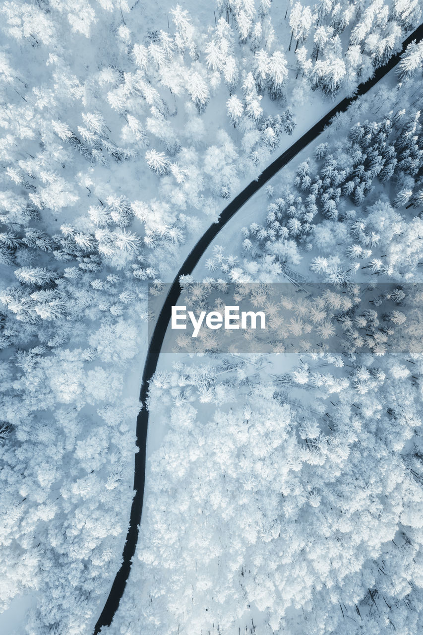 Wintery aerial view at road winding through forest covered in deep snow, austria.