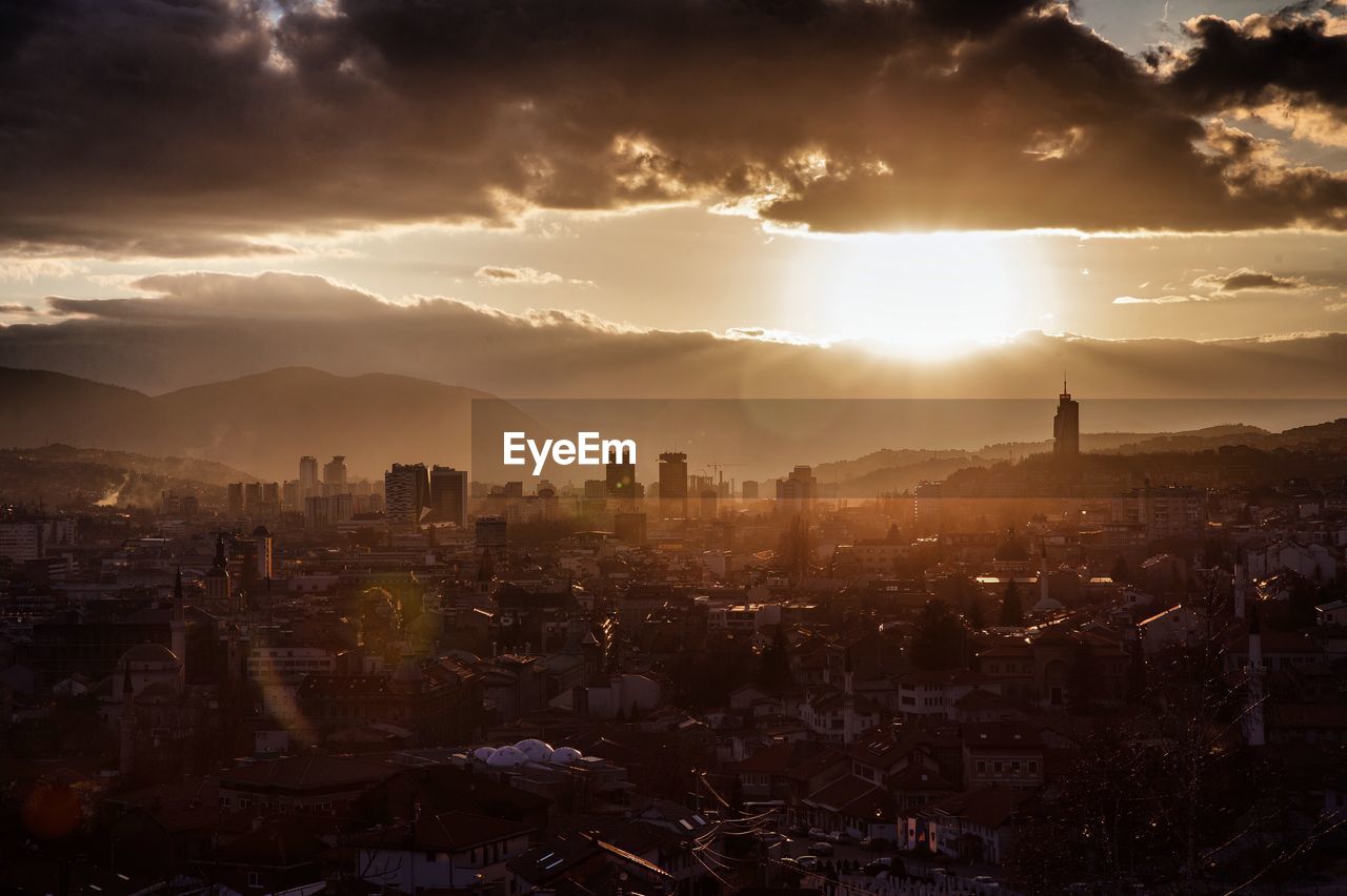 HIGH ANGLE VIEW OF BUILDINGS AGAINST SKY AT SUNSET