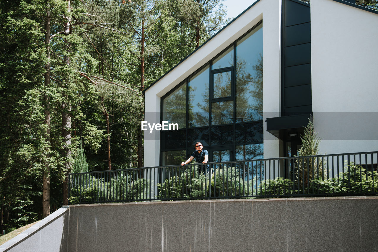 MAN ON RAILING AGAINST BUILDING