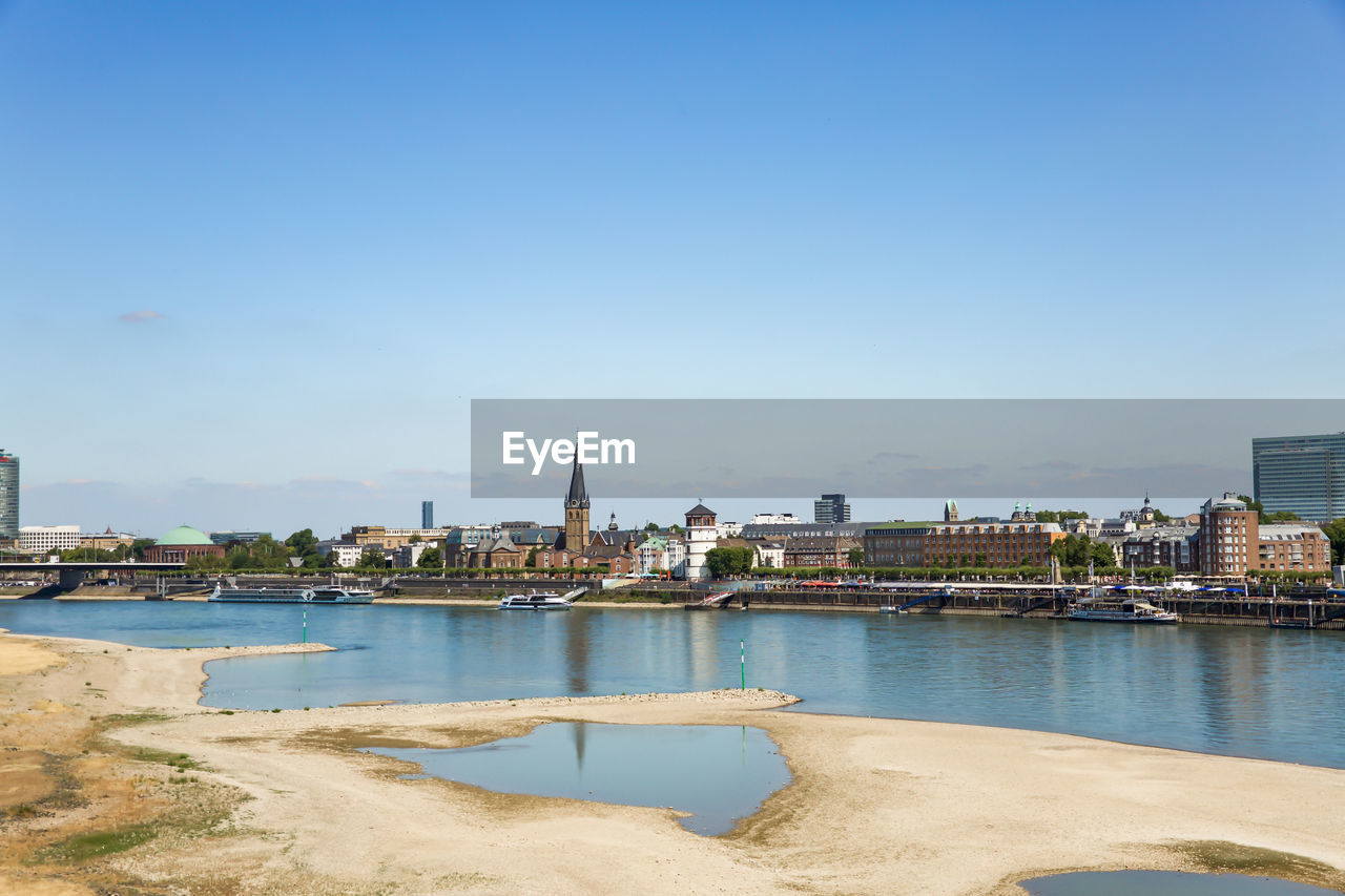 VIEW OF BUILDINGS BY RIVER AGAINST SKY