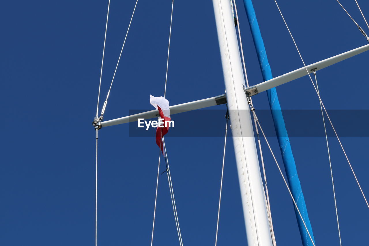 Low angle view of sailboat mast against clear blue sky