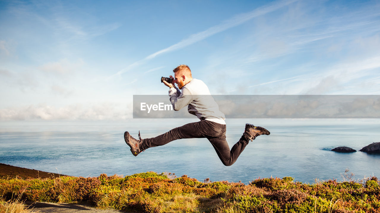 FULL LENGTH OF YOUNG MAN JUMPING IN SEA