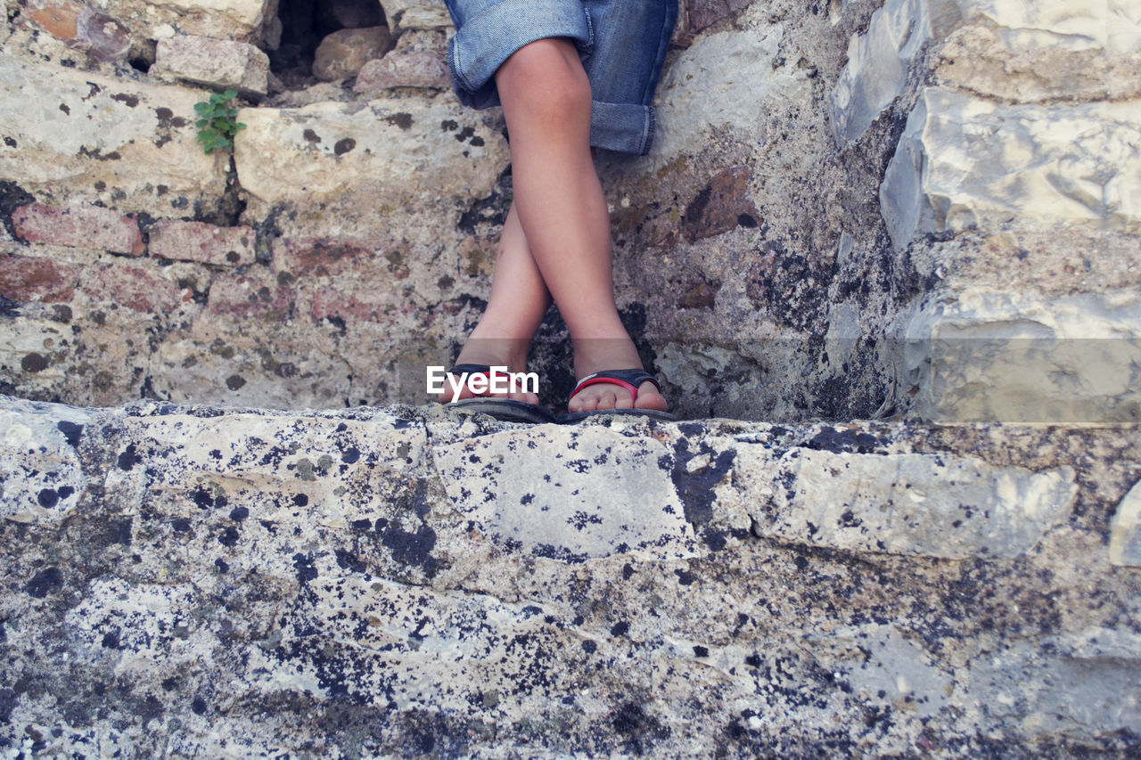 Low section of kid standing on stone wall