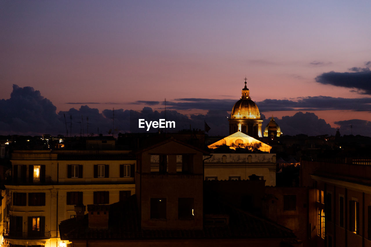 Illuminated buildings against sky at sunset