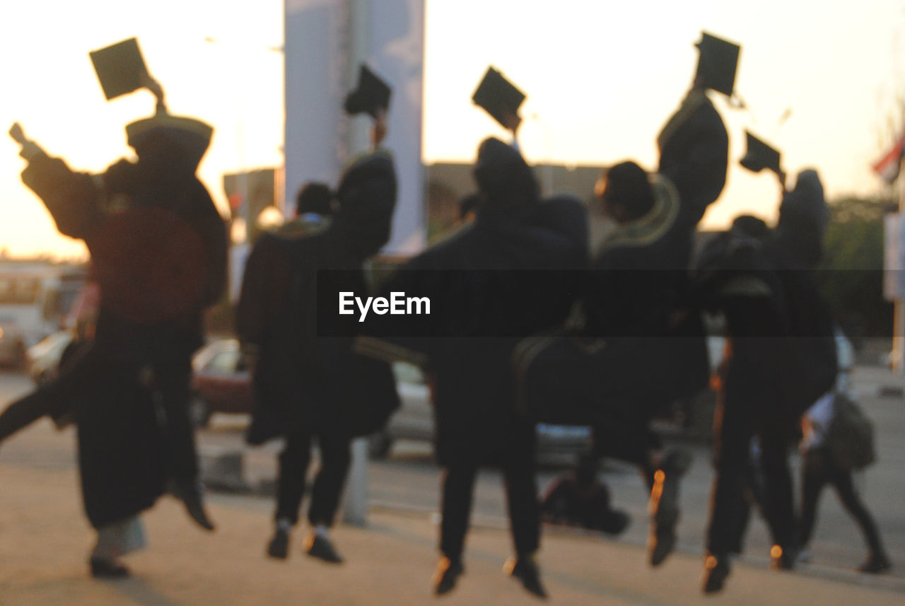 Rear view of excited students throwing mortarboard during graduation