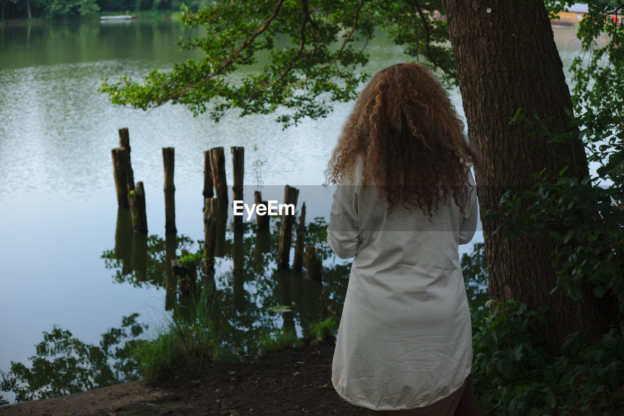 Rear view of woman standing against lake