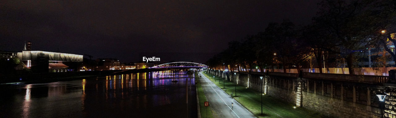 ILLUMINATED CITYSCAPE BY TREES AT NIGHT