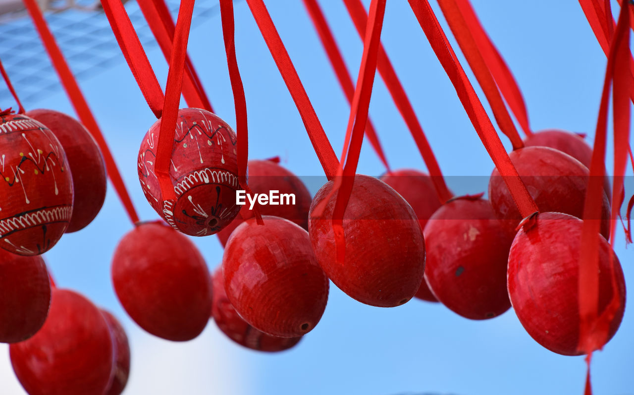 Close-up of easter eggs hanging from ribbons against sky