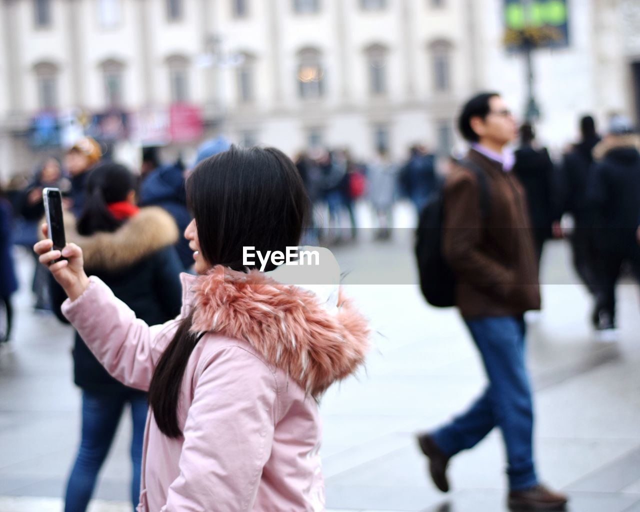 Side view of woman taking selfie in city